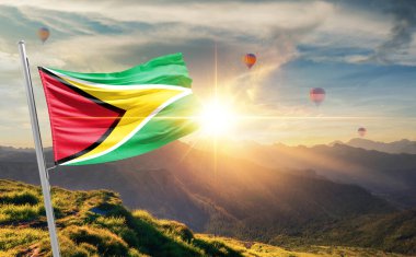 Guyana arka planda sıcak hava balonlarıyla günbatımında bayrak sallıyor 