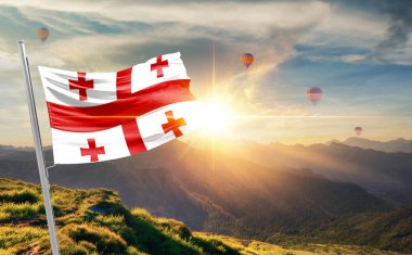 Gün batımında arka planda sıcak hava balonlarıyla Georgia bayrağı sallıyor 