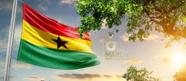 Gana günbatımına karşı ağacın yanında bayrak sallıyor.