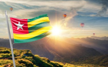 Togo arka planda sıcak hava balonları ile günbatımında bayrak sallıyor 