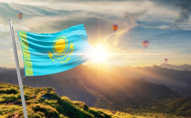 Kazakistan arka planda sıcak hava balonlarıyla gün batımında bayrak sallıyor 