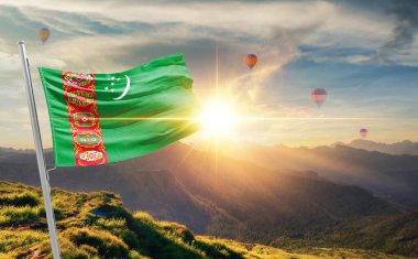 Türkmenistan arka planda sıcak hava balonlarıyla gün batımında bayrak sallıyor 