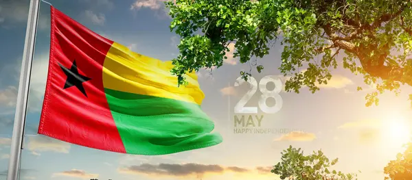 Gine-Bissau ulusal bayrağı ağaçların yanında dalgalanan bulutlara karşı