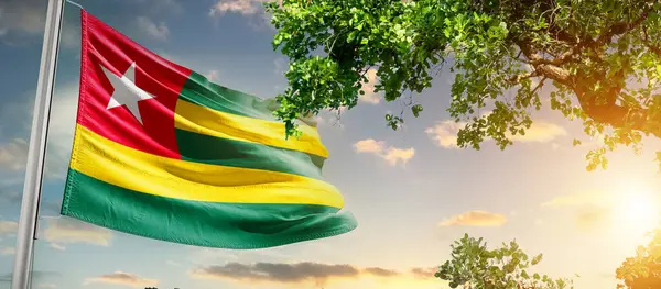Togo ulusal bayrağı ağaçların yanında dalgalanan bulutlara karşı