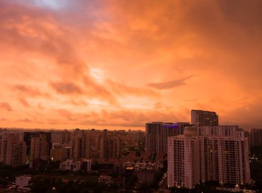 Gurgaon, Haryana, Hindistan 'ın renkli günbatımı. Modern mimari, ticari, lüks apartman binaları olan Gurugram kentsel gökyüzü manzarası. Delhi NCR bulutlu güzel şehir manzarası, şehir ışıkları..