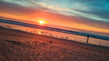 Huzurlu sahil sahnesinin görüntüsü kumsalda gün doğumu ve turist yürüyüşü