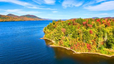 Kıyı ve mavi suları kaplayan güz ağacı ormanıyla gölün üzerindeki Aerial görüntüsü