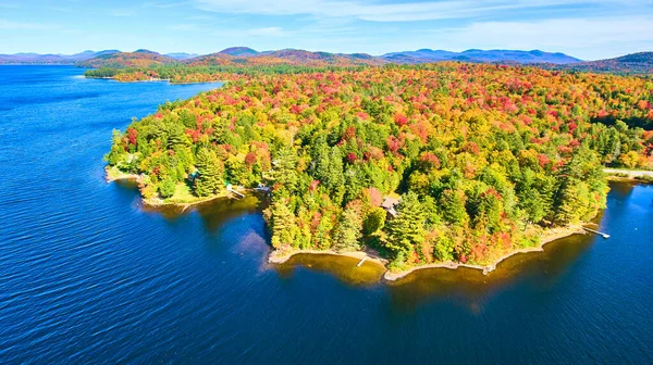 Image of Blue water lake aerial focused on coastline filled with fall forests and mountains