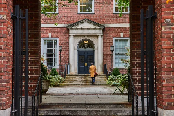 Image of Law student walking through courtyard from brick arches in New York City straight on