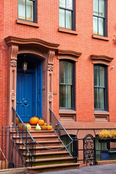 Image of Brick building with steps up to blue door and pumpkins on porch in Greenwich Village New York City