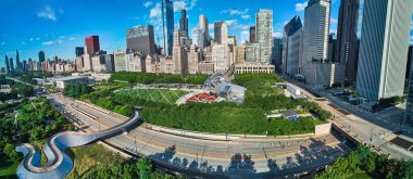 Chicago şehir merkezindeki yürüyen köprü ve tiyatroyla Millennium Park 'ta gökdelenlerle çevrili bir görüntü