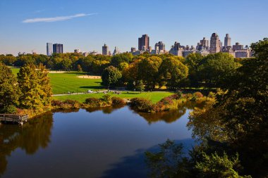 Central Park 'ta New York şehrinin arka planında bir Gölet resmi