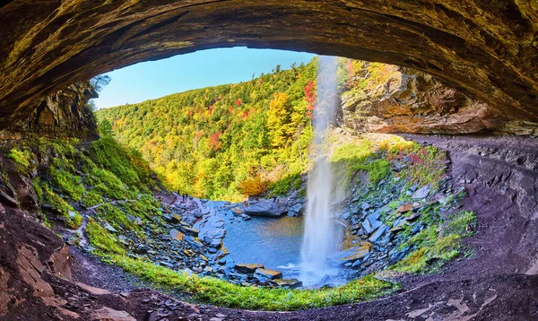 Image of Panoramic view behind waterfall in rocky cavern cliffs with fall foliage mountains in background
