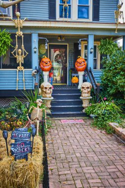Amerika 'da Cadılar Bayramı için balkabakları ve iskeletlerle süslenmiş bir ev resmi.