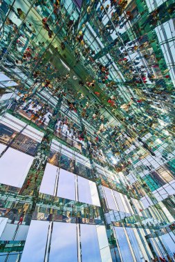 Uçsuz bucaksız cam aynaların görüntüsü yüzlerce küçük turisti yukarı bakarken gösteriyor.