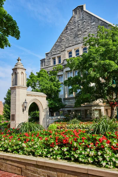 Image of Red summer flowers by Sample Gates entrance to university at Indiana University