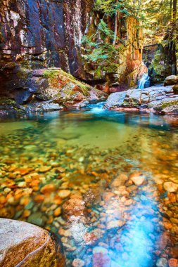 Arka planda şelaleli ve küçük kayalıklı berrak nehir suyu görüntüsü