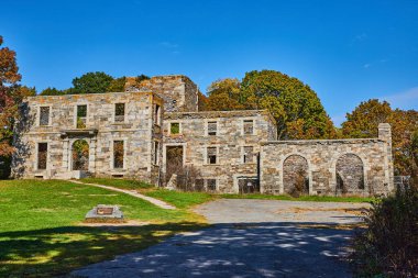 Ormandaki kemerli ve açık pencereli terk edilmiş eski taş yapının resmi