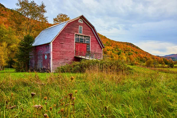 Image of Red barn in country fields surrounded by mountains of peak fall foliage trees