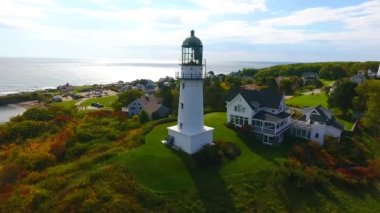 Tepe üzerinde evleri ve yaprakları olan beyaz deniz fenerlerinin etrafındaki havadan tavanın videosu.