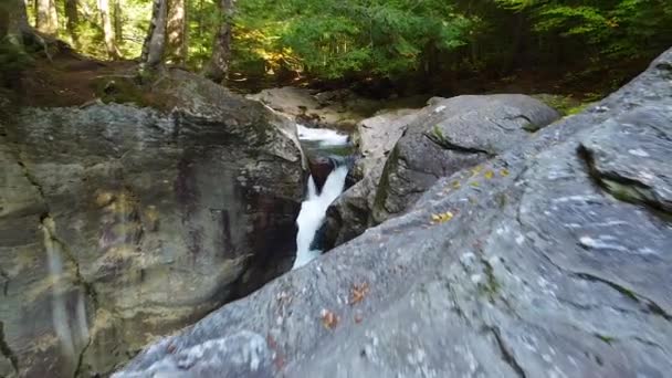 空中倒挂镜头 穿过令人惊叹的岩石 被瀑布划破峡谷 坠入被苔藓茂密的森林环绕的蓝色水域 — 图库视频影像