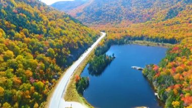 Mavi gölün üzerinden uçan ve New Hampshire 'ın sonbahar yaprak dağları üzerinde turist manzaralı bir video.