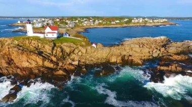 Maine kıyısındaki Nubble Deniz feneri adası boyunca okyanus dalgaları ile uçan tavanın videosu.