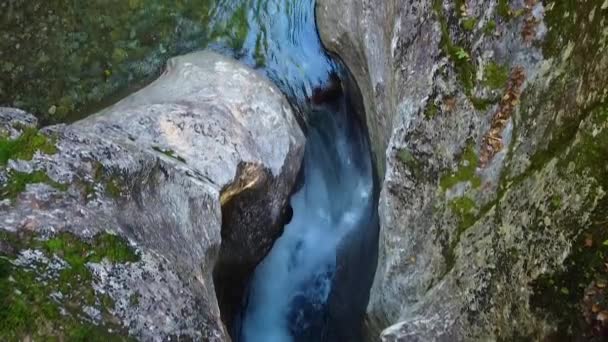 空中平底锅正好在岩石巨石峡谷内 小瀑布落在蓝色的水中 被落叶和苔藓环绕在悬崖峭壁中 — 图库视频影像