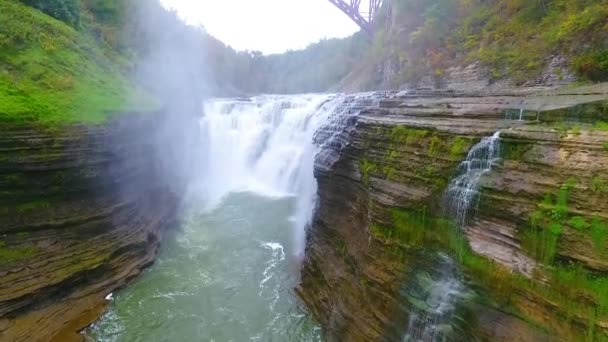 鋼の月の橋から美しい荒れ狂う滝までの空中のビデオ緑豊かな森の中で層状の崖を切断 — ストック動画