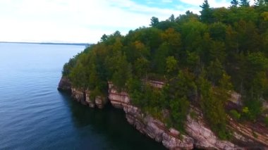 Vermont kıyısındaki kayalıklara yakın yemyeşil ormanlı Aerial 'ın videosu.