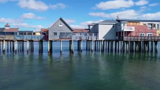 店に覆われた大きな木製の桟橋の上にメイン海のビーチの周りに空中パンのビデオ — ストック動画