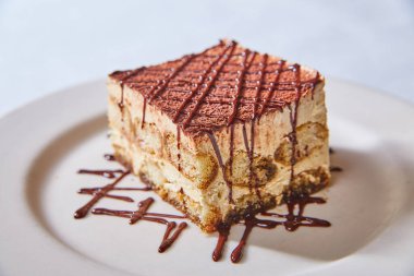 Tatlı, tatlı, şeker, tiramisu bayan parmaklı İtalyan görüntüsü çikolata yağmurlu beyaz tabak arka planına iyi gelir.