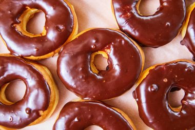 Beyaz tepsi arka planında delik olmayan çikolatalı donutların aşağı doğru görüntüsü