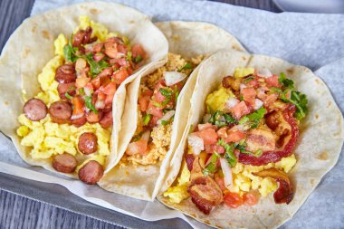 Meksika usulü kahvaltılık taco sosisli, pastırmalı, sosisli, sosisli, soğanlı, unlu tortilla.