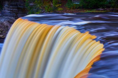 Tahquamenon Şelalesi 'nde beyaz ve altın rengi şelaleli yumuşak mavi suların görüntüsü