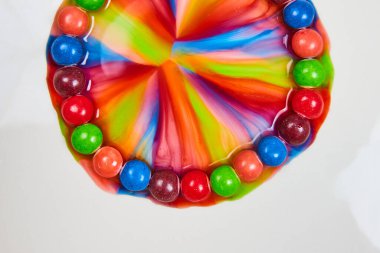 Skittles şekerleri ile su karışımı renkli gökkuşağı görüntüsü ve beyaz bir arkaplan varlığı üzerine şeker yaymak