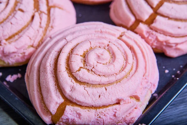 シングルピンクのストロベリーペストリーのイメージ焼き良いメキシコの甘いパンコンチャス貝殻の渦巻きの霜降り — ストック写真