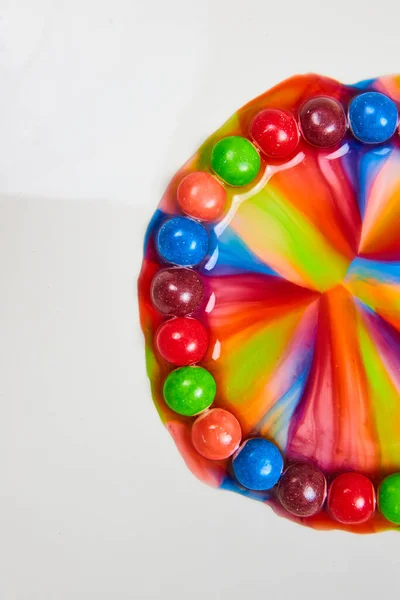 Image of Skittles candy with sugar and water merge into colorful rainbow portal in vertical background asset with white behind it