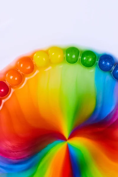 Image of Vertical dome of skittles rainbow candy as sugar and water mix into a psychedelic hippie flower on a white background asset
