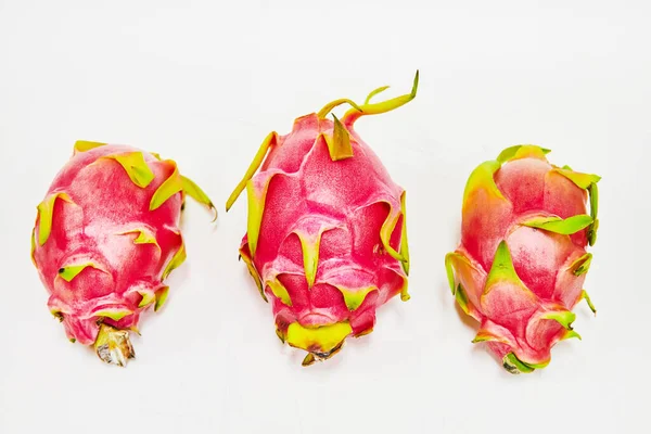 Image of Three dragon fruit with pink and yellow exteriors on white background