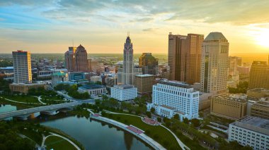 Image of Scioto River with skyscrapers Columbus Ohio bathed in warm yellow sunrise glow aerial clipart