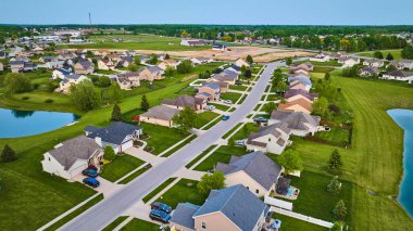 İki göletin havadaki banliyö mahallesinin görüntüsü yeşil çitler ve uzak konut inşaatı