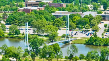 PFW kampüsündeki parlak yaz gününün görüntüsü. Ron Venderly Aile Köprüsü, binalar ve nehir havası.
