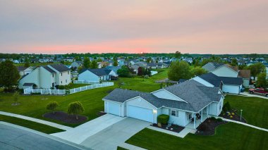 Uzak ağaçlar ve komşu evlerle ufukta gün batımı görüntüsü beyaz bahçe çitleri