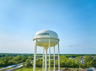 Uzaktaki yeşil ağaçlar ve mavi gökyüzü ile Havadan Beyaz Huntertown su kulesinin görüntüsü