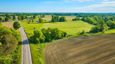 Image of Plowed dirt field with nearby green farmland in rural country area aerial drone shot clipart