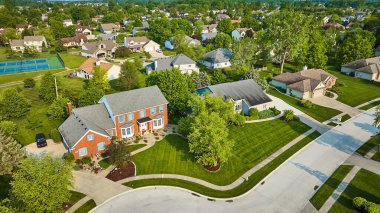 Brick House 'un mavi panjurlu görüntüsü ve tenis kortlu muhitte yeni biçilmiş çimen.