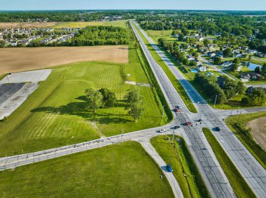 H yolu kesişiminin görüntüsü bir tarladaki uzak evler ve ağaçlarla birlikte.