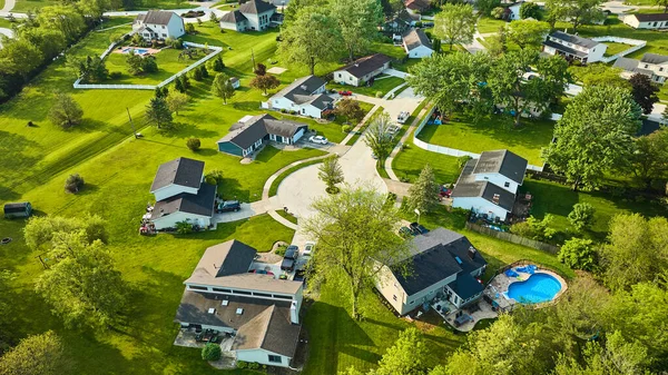 Image of Middleclass suburban neighborhood small cul-de-sac and two in ground pools aerial