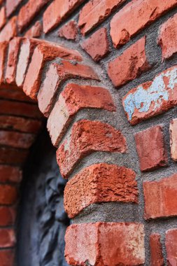 Sol tarafında kısmi siyah yükseltilmiş motifli, eğimli kırmızı tuğla duvar ve çıkıntılı kemer yolu görüntüsü